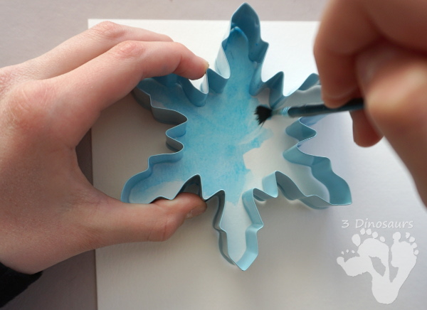 Fun to Make Watercolor Snowflakes - make fun snowflake themed painting using cookies cutters - 3Dinosaurs.com #watercolorforkids #cookiecuttes #paintingforkids #finemotorskills #winteractivitiesforkids
