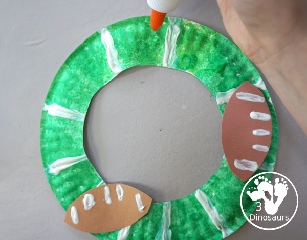 Football Wreath Craft For Kids - a fun wreath craft for a football theme. You have a green wreath with white lines and footballs around the wreath. Great for any football theme. - 3Dinosaurs.com