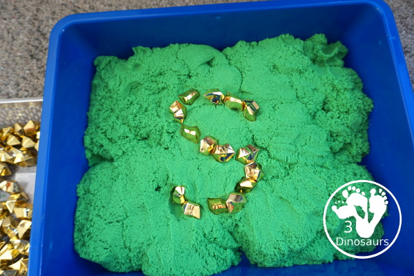 St. Patrick's Day Gold Find Sensory Bin - a fun kinetic sand sensory bin for St. Patrick's Day with finding the gold in the sensory bin - 3Dinosaurs.com