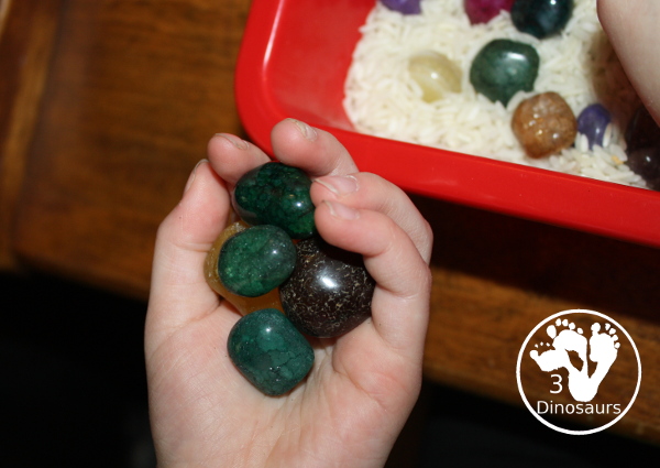 Rock & Rice Sensory Bin - Holding rocks in their hands from the sensory bin. - 3Dinosaurs.com