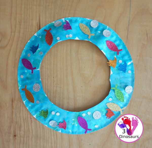 Ocean Wreath with Glitter Fish - A great wreath you can make with an ocean theme. It is a simple and easy-to-make craft for kids of different ages. You have a paper plate, glitter paper, glue and fish punches. - 3Dinosaurs.com