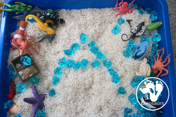 Ocean Rice and Rock Sensory Bin - a simple rice base sensory bin that has ocean animals and blue acrylic rocks in the bin. A simple sensory bin for any ocean theme - 3Dinosaurs.com
