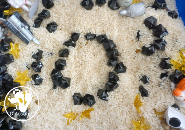 Space Sensory Bin With Rice and Rocks - you have space figures, yellow stars, and rice for this simple sensory b8in. This is great for a space theme with kids. And they will enjoy exploring space themes in the sensory bin. A fun sensory bin for kids in preschool, prek and kindergarten. - 3Dinosaurs.com
