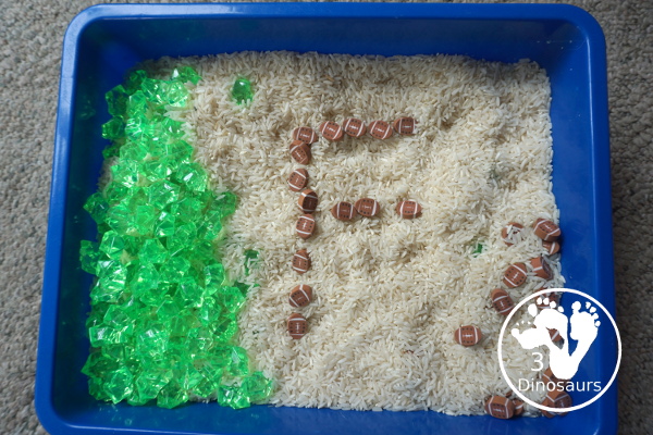Football Sensory Bin - a simple football sensory bin for kids. You have a mix of green rocks, rice and footballs - 3Dinosaurs.com